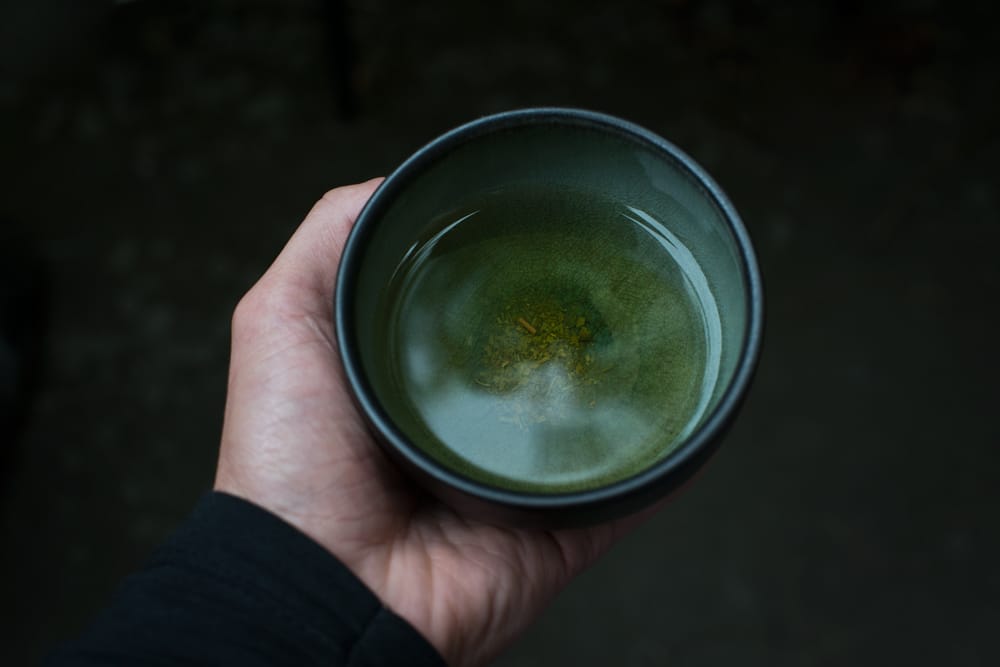 Hand holding a bowl of tea. Koan.