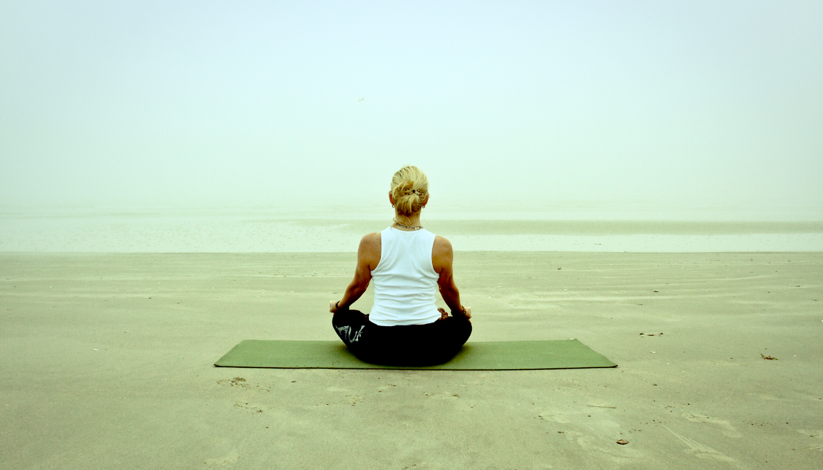 Woman meditating on a foggy beach