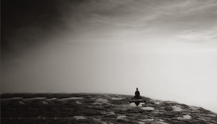 Buddha statue sitting on rocks.