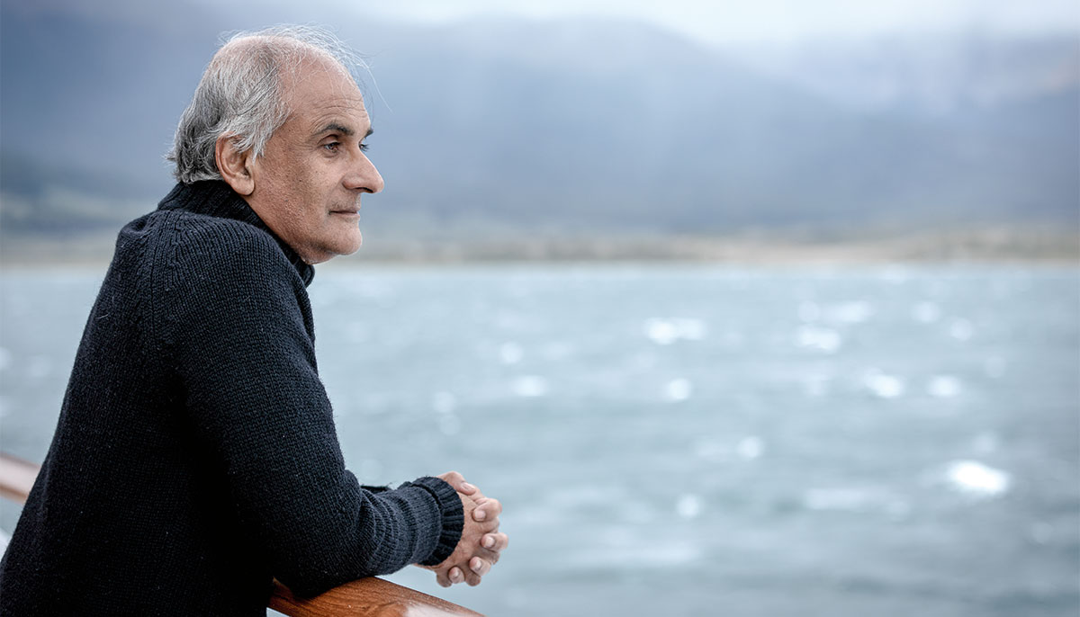 Pico Iyer looks over railing at water.