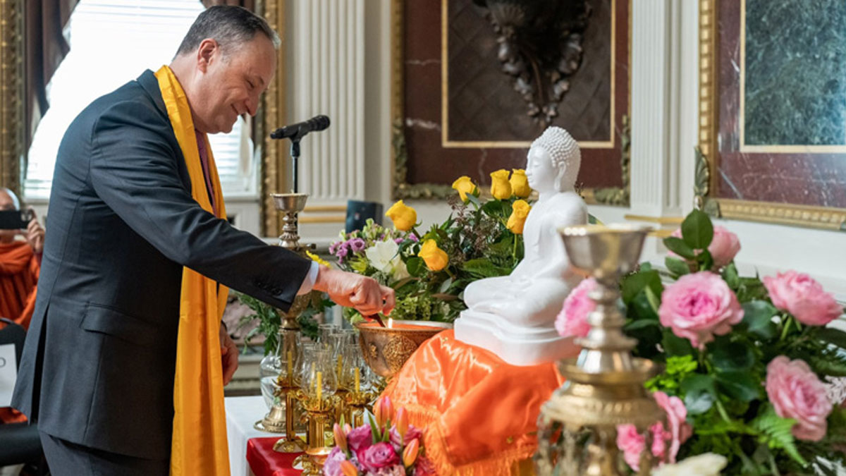 Second Gentleman Mr. Douglas Emhoff lights a candle in front of a white statue of the buddha