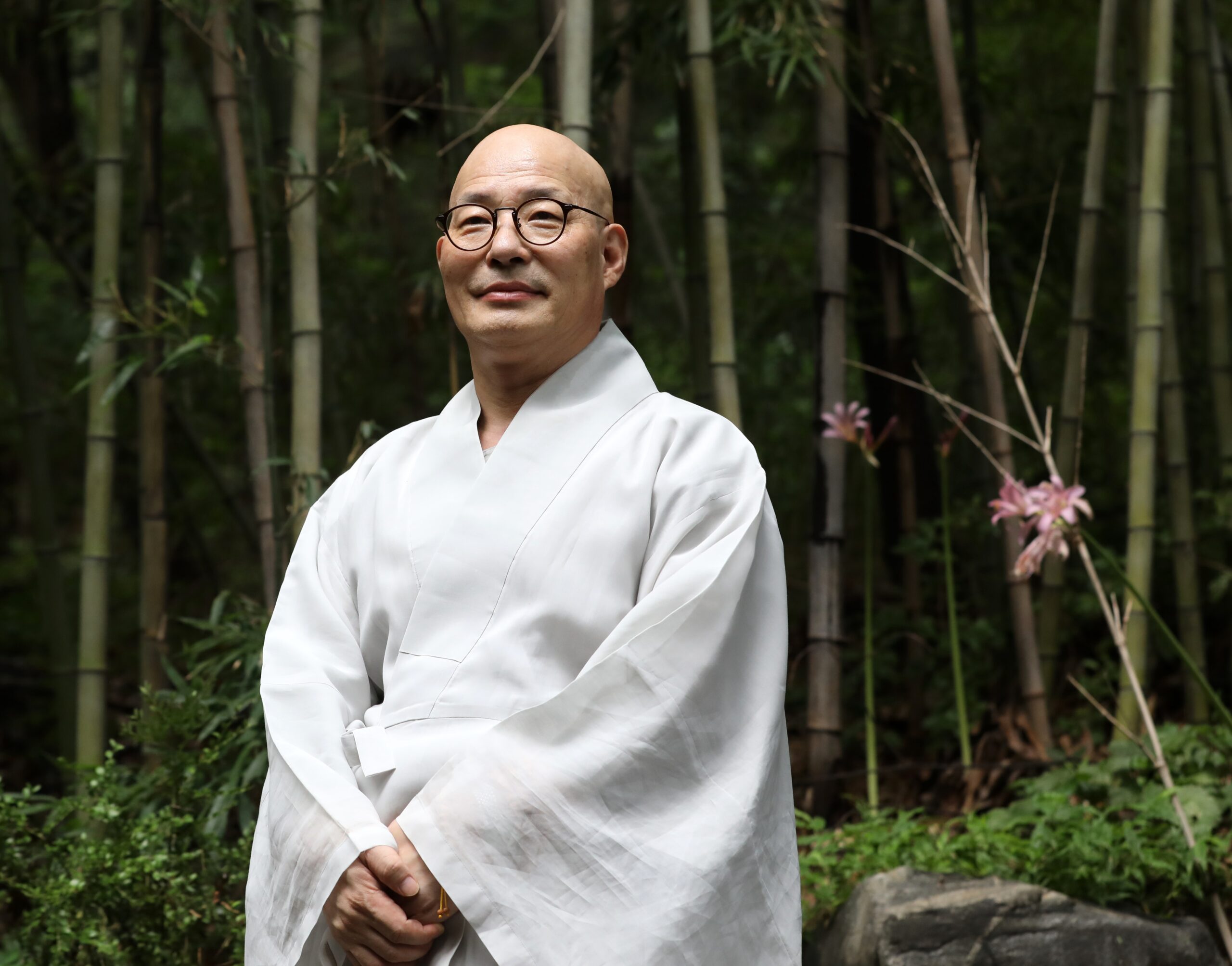 Monk Jin Woo is pictured standing and smiling.
