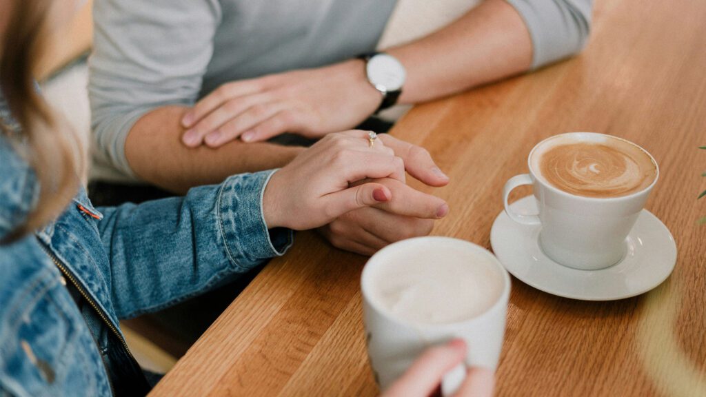 Couple holding hands over coffee