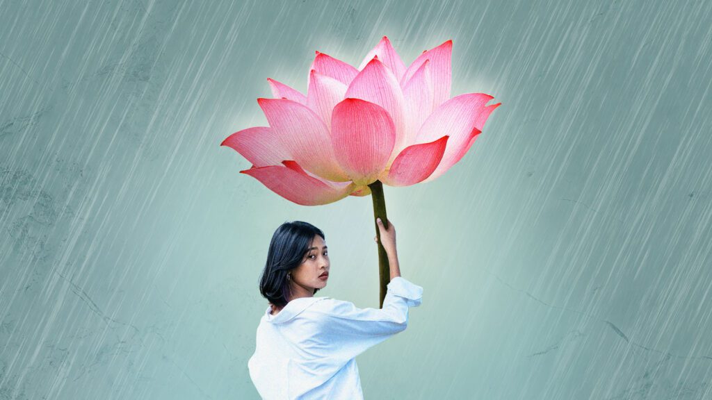 A woman holding a lotus flower as an umbrella.